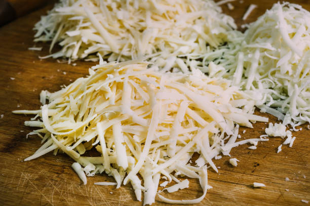 Shredded cheese on a wooden cutting board. Three different kinds of Shredded cheese on a wooden board. The concept of cooking. Macro food photo close up shredded mozzarella stock pictures, royalty-free photos & images