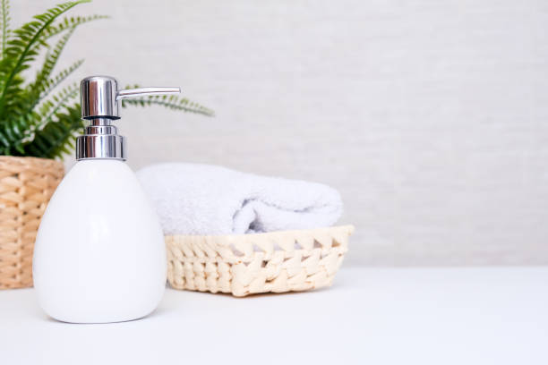 istock White ceramic soap dispenser, spa towel and green plan on white counter table inside a bright bathroom background with copy space 1296026945