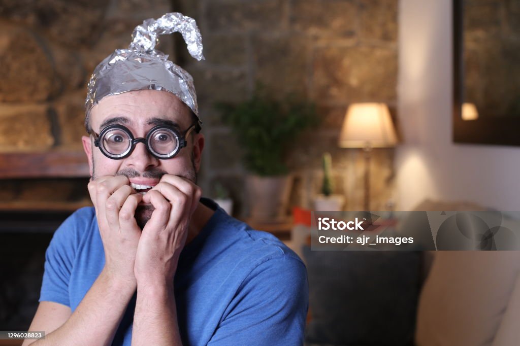 Distrustful man wearing weird tinfoil hat Distrustful man wearing weird tinfoil hat. QAnon Stock Photo