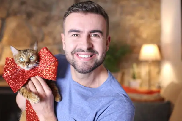 Photo of Man holding cat with red ribbon