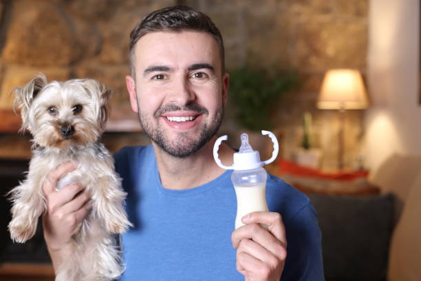 istock Man holding small dog and feeding bottle 1296029467