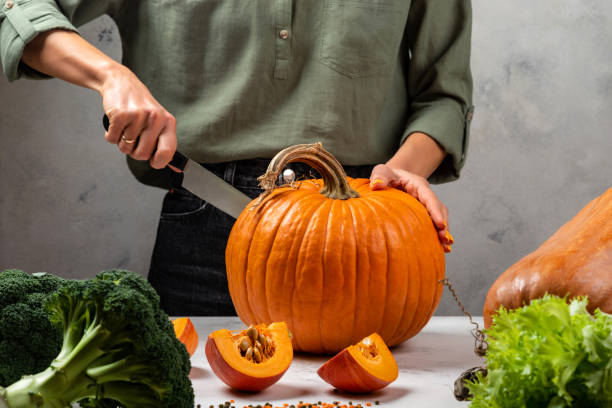 istock Female hands cutting pumpkin on the kitchen. Close-up. 1296029535