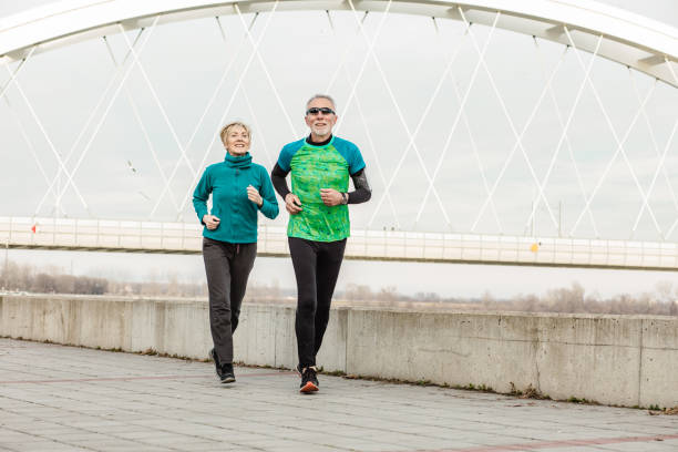 istock Senior couple jogging by the river 1296030171