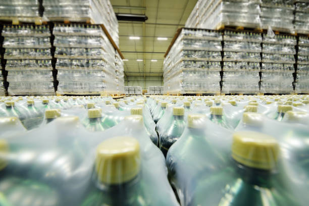 istock huge industrial warehouse with plastic food wrap wrapped plastic bottles with carbonated drinks, water or beer. 1296034012