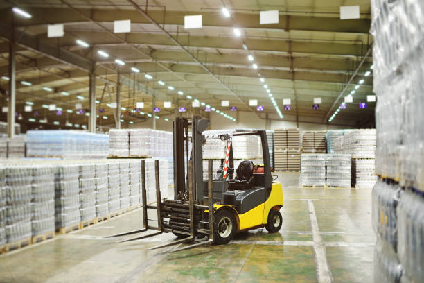 loader on the background of a huge industrial food warehouse with plastic pet bottles with beer, water, drinks. - empilhadora imagens e fotografias de stock