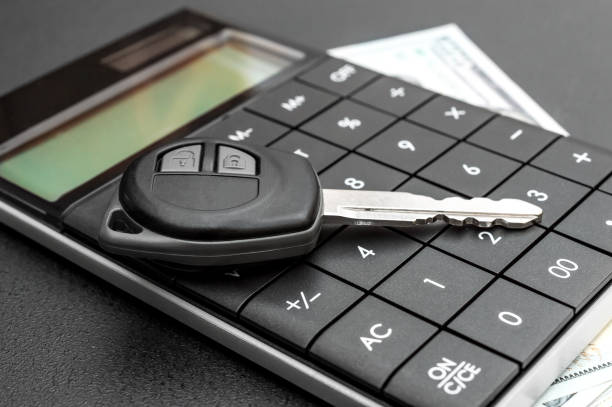 Car key with calculator and money on black background.