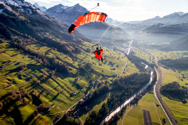 Paraglider flies through clear skies in the morning Sunny Swiss Alps below parachuting stock pictures, royalty-free photos & images