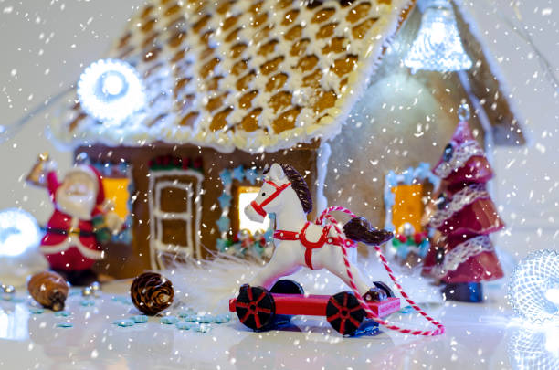 istock Gingerbread house decorated with glaze on a light background. Holiday decorations. Figurines of a Christmas tree, a horse and Santa Claus 1296036437