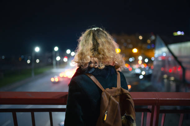 istock Woman looking at the night city from a bridge 1296038111