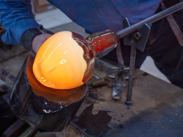 istock Artisan hands working with hot malleable glass on glassblower whistle. 1296040573