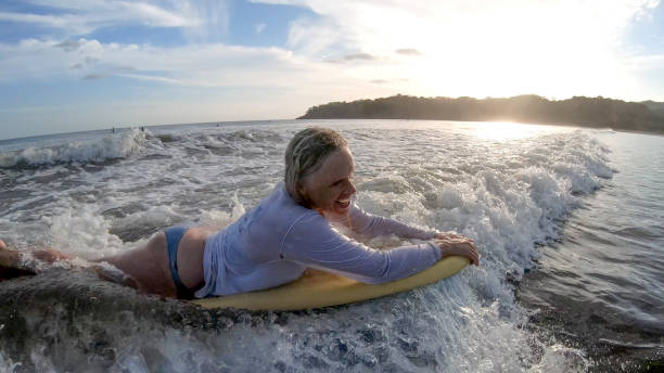 vista da mulher boogie-boarding através de água branca na parte da manhã - bodysurfing - fotografias e filmes do acervo