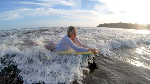 vista da mulher boogie-boarding através de água branca na parte da manhã - bodysurfing - fotografias e filmes do acervo