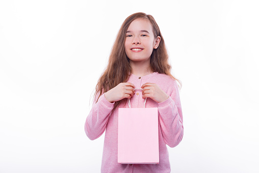 Portrait of cheerful child girl holding pink shopping bag.