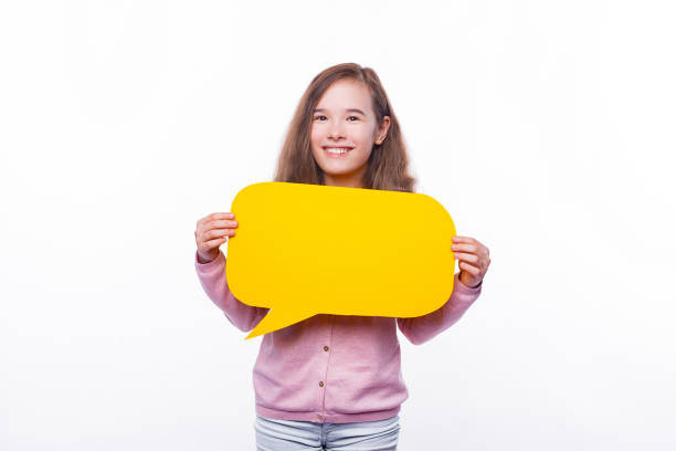 istock Smiling cute young girl holding yellow speech bubble 1296041646