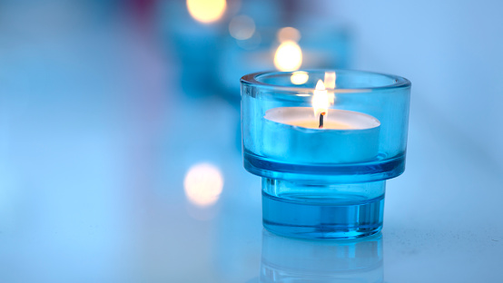 tealight against blue background in glass with copy space