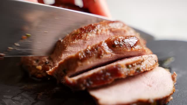 Woman cuts juicy duck fillet with knife.