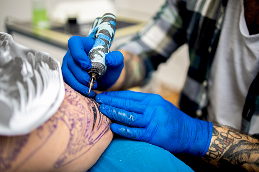 Tattoo artist working on eagle tattoo in a studio.