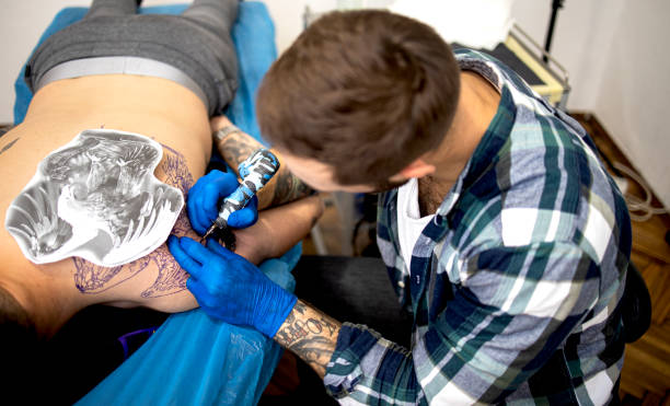 istock Tattoo master draws on the customer’s arm stock photo 1296048190