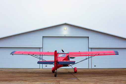 Small single prop engine aircrafts planes parked inside workshop hangar with closed door. Private ultralight at aerodrome