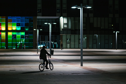 unrecognizable young adult man riding on his vintage bicycle at night in the city