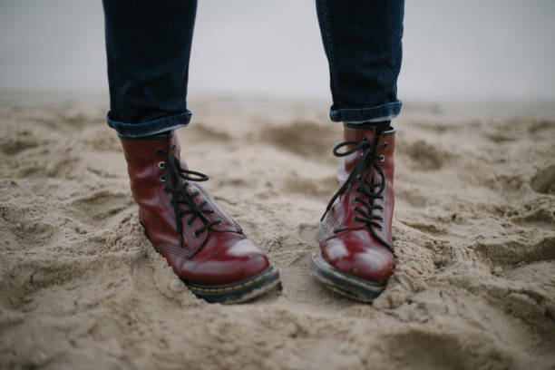 Red dirty hipster boots in the sands with dark blue jeans seashore