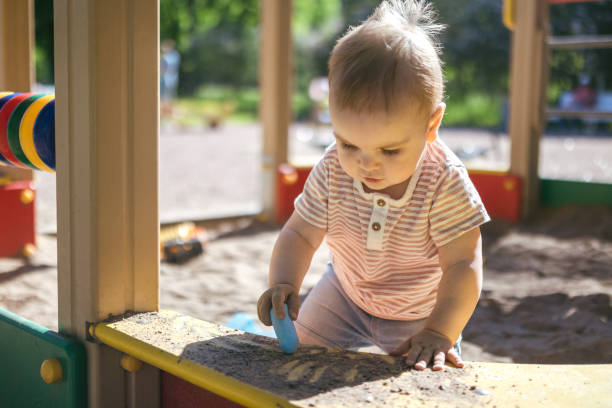 One year old toddler playing in the sandbox