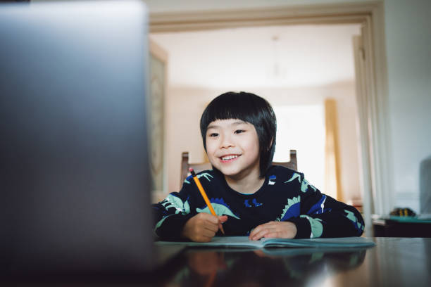 istock Asian little boy attending to online class and working on his exercise from home 1296052818