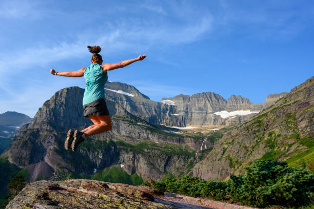 女性はグリンネル氷河で腕を出して飛躍する - exploration mountain ice jumping ストックフォトと画像