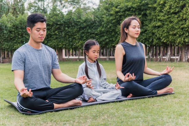 istock mother, father practicing doing yoga exercises with child daughter outdoors in meditate pose together 1296067320