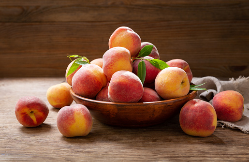 bowl of fresh peaches on a wooden background