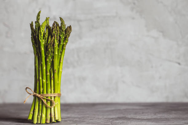 istock Fresh bunch of asparagus with smooth daylight on grey stone background/top view 1296067757