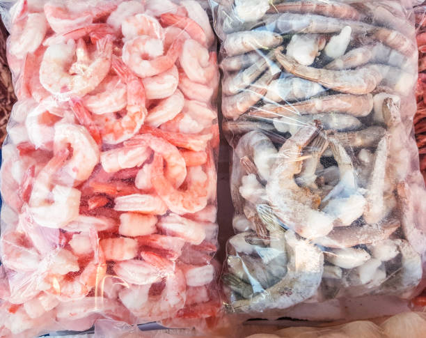 Two large plastic bags of frozen raw and cooked shrimp, on the counter of the fish market stock photo