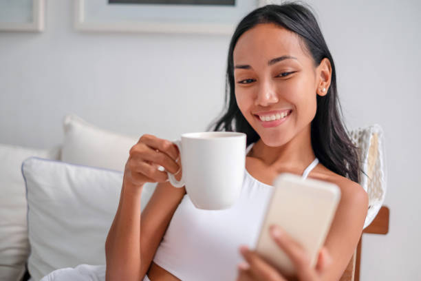 istock Beautiful Indonesian woman smiling while reading text message 1296071882