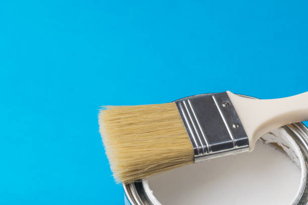 istock Brush with long bristles on an open can of paint on a blue background. 1296074564