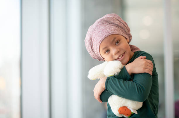istock Young girl with cancer hugging her teddy bear 1296076120