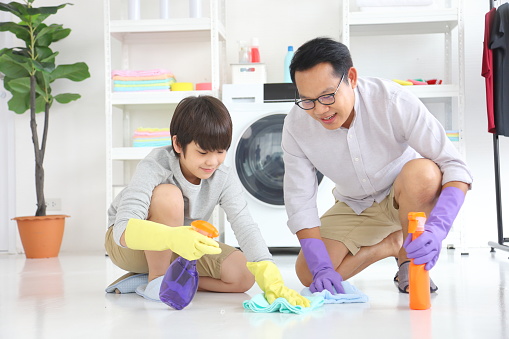 Asian father and son help each other to clean the floor for daily routine chores and housekeeping concept
