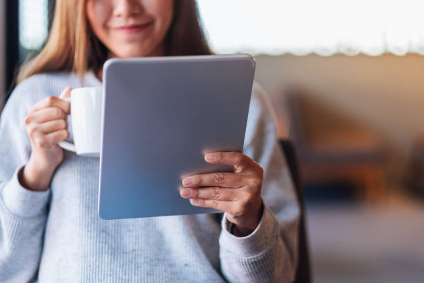 istock a beautiful young asian woman holding and using digital tablet while drinking coffee 1296083656