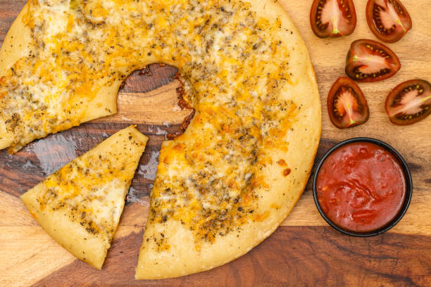 istock Classic cheesy bread topped with herb garlic spread, and cheese blend served with marinara sauce and tomatoes close up on wooden board directly from above 1296087535