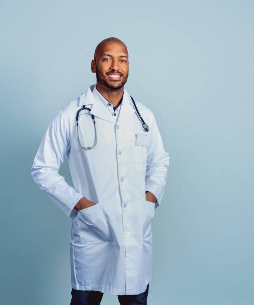 istock Smiling male doctor standing with hands in pockets 1296092762