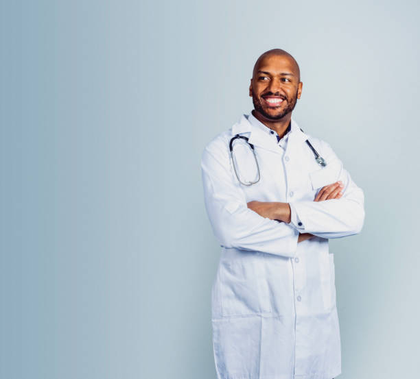 smiling male doctor standing with arms crossed - olhar para longe imagens e fotografias de stock