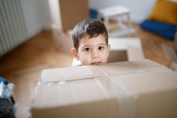 istock Toddler holding a cardboard box and looking at camera 1296093024