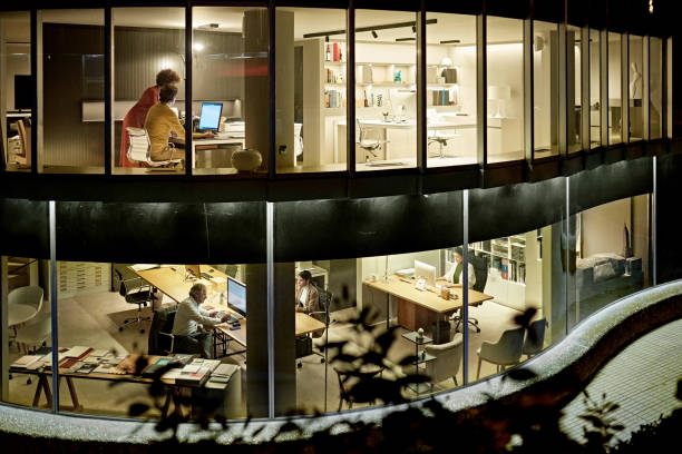 visione a due piani dei professionisti del design che lavorano di notte - office indoors contemporary office building foto e immagini stock