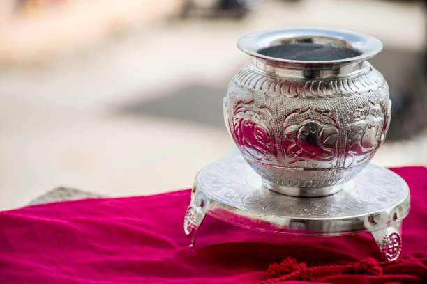 Beautiful carved silver pot or kalash and stand used in hindu rituals, on blur background. stock photo