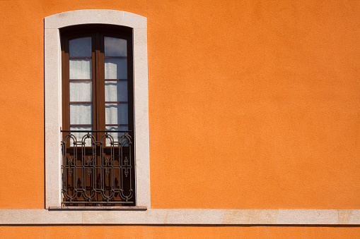 View of antique wrought iron window on a stone facade. Spanish Traditional ornaments.
