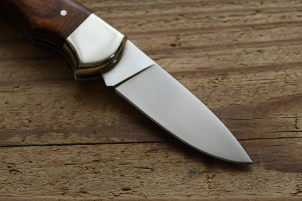 istock Folding knife on wooden background. 1296101271