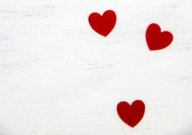 istock Three bright red hearts on a light wooden background. Copy space, top view. Congratulations on the day of lovers 1296103850
