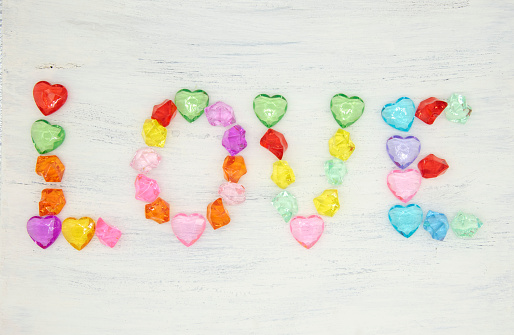 The word love is made up of colored glass stones on a light background.