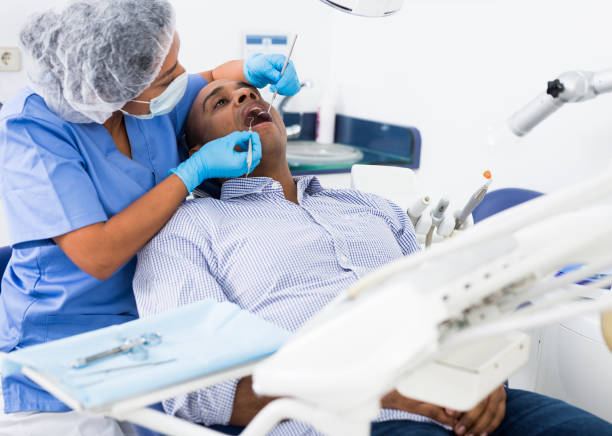 istock Man sitting with open mouth during dental checkup at dentist 1296105327