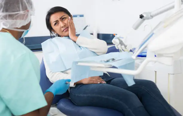 Photo of Woman patient talking to dentist and complaining of toothache