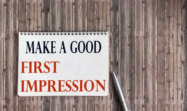Photo of Make a good first impression written on notepad and wooden table